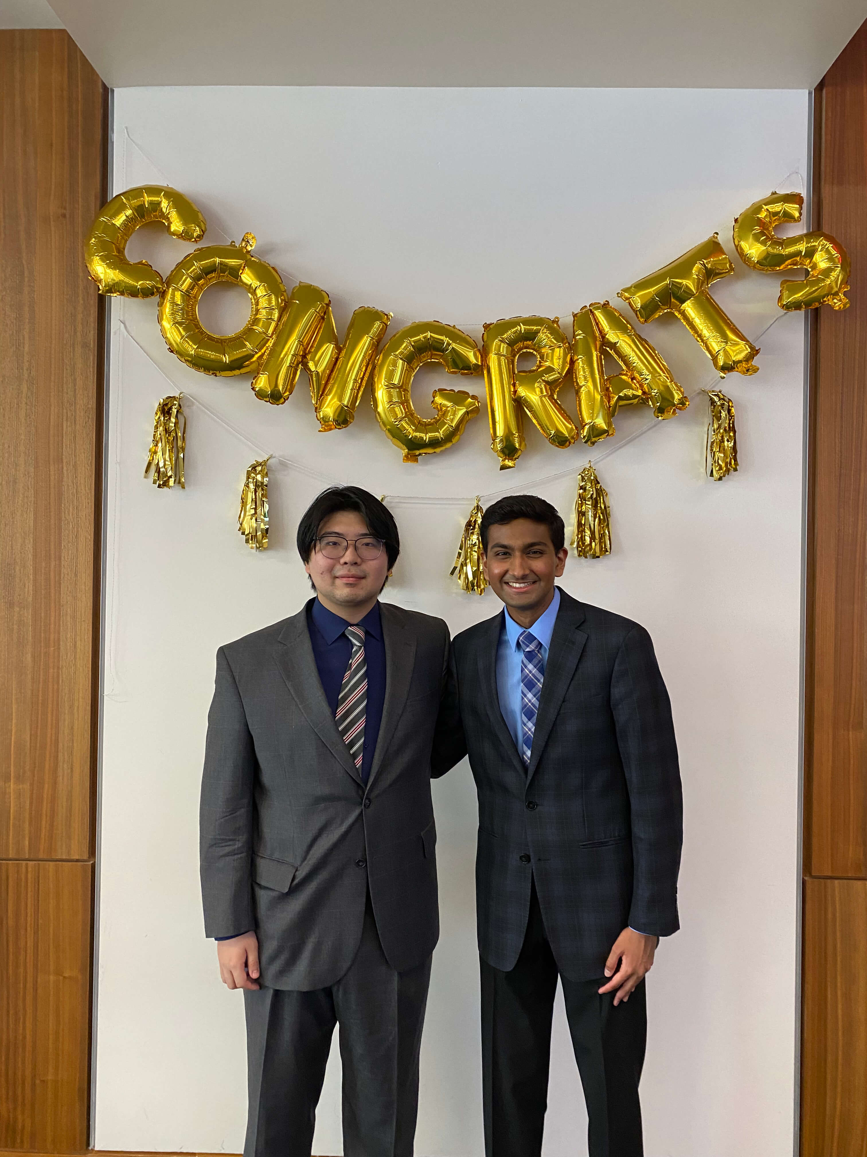 Rohan Patil celebrating achievements with team member under congratulations balloons