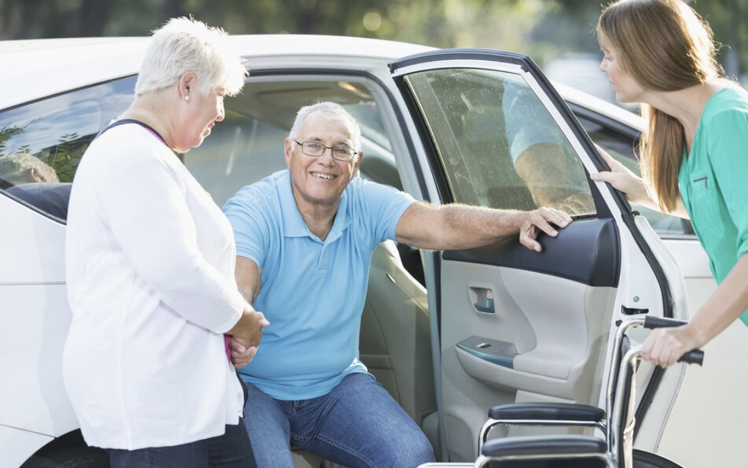 Senior man being helped into a car by caregivers for transportation services